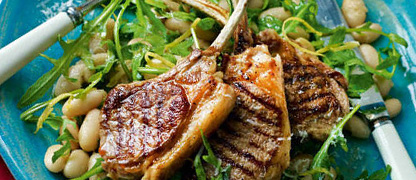 Lamb cutlets resting on a bed of cannellini beans and wild rocket